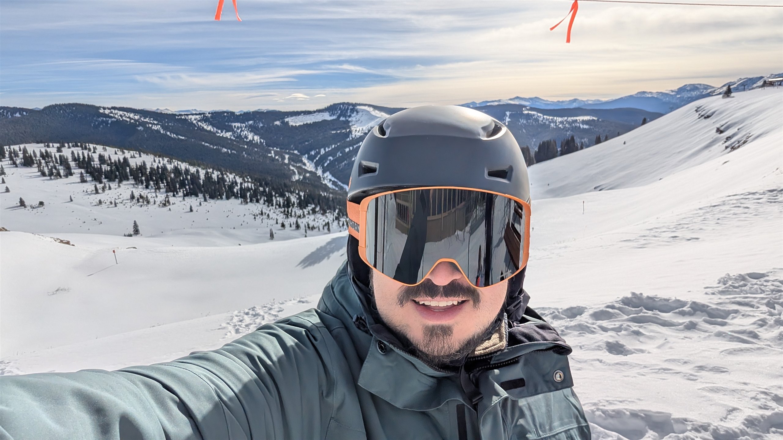 Almaz Dolubaev in helmet and mirrored goggles taking a selfie above a snowy alpine valley